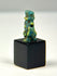 Side profile of Ancient Egyptian Bes faience figure with suspension hole through torso