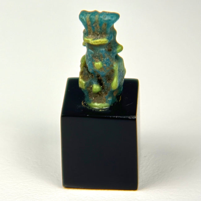 Rear view of Ancient Egyptian Bes faience amulet showing surface wear and glaze texture