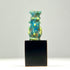 Ancient Egyptian faience amulet of deity Bes in turquoise-blue glaze on display cube