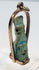 Reverse view of an ancient Egyptian amulet with weathered glaze and mineral deposits