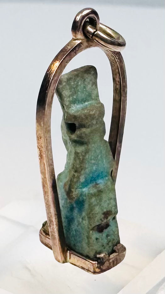 Reverse view of an ancient Egyptian amulet with weathered glaze and mineral deposits