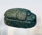 Top view of ancient Egyptian blue faience scarab showing carved head, thorax, and wings