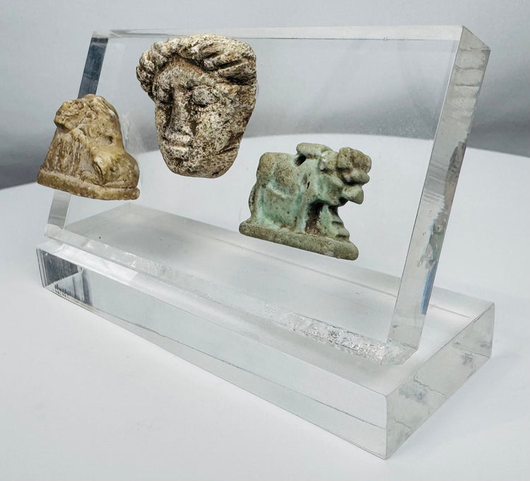 Faience Hathor amulet accompanied by carved stone lion and classical portrait fragment from antiquity.
