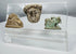 Collection of three archaeological artifacts from the ancient Mediterranean world presented in a modern acrylic display.