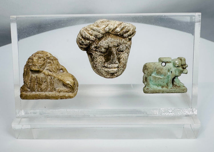 Ancient Egyptian and Greco-Roman antiquities mounted in a clear display case featuring religious and figural carvings.