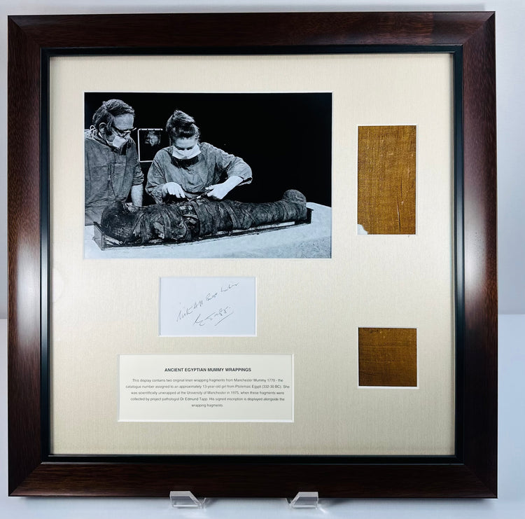Framed mummy-wrapping display showing ancient linen, documentary photograph and accompanying notes beneath glazing.