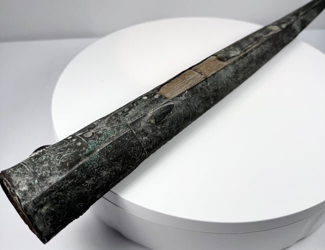 Wooden scabbard liner with two irregular openings separated by a central section of wood.