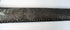 Metal sword sheath with red and dark cabochon inserts and green surface corrosion.