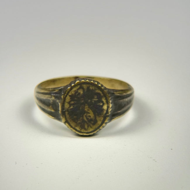 Ancient Near Eastern bronze signet ring with ornate floral motif and aged patinated finish
