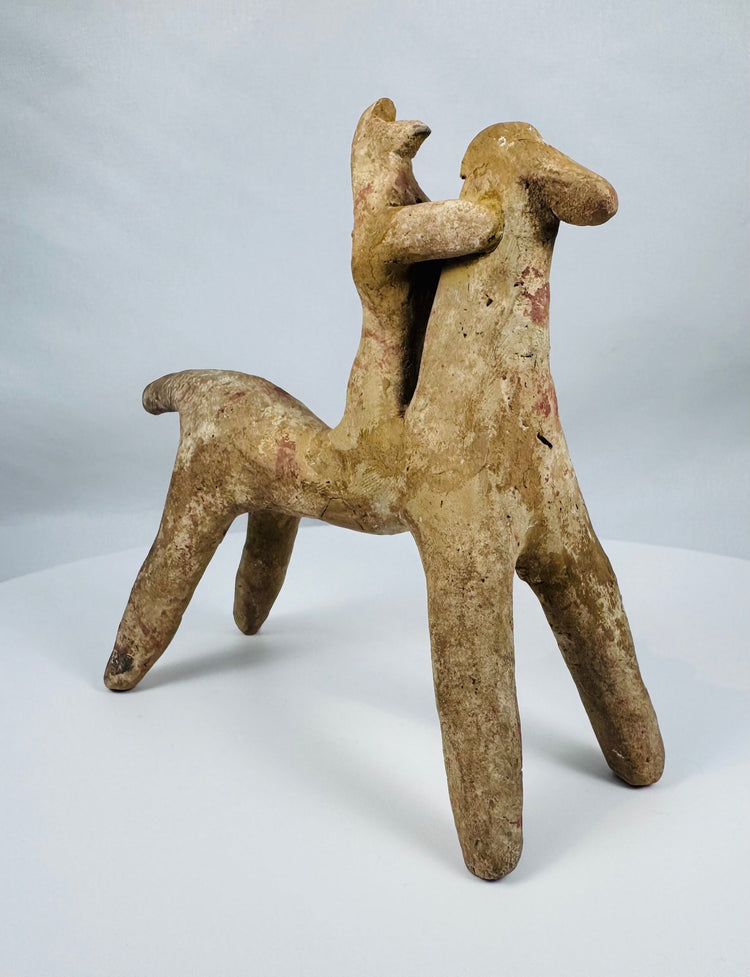 Pre-Classical Greek terracotta equestrian figure from Boeotia with surviving red pigment and mineral deposits.