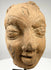 Frontal close-up of ancient Indian terracotta sculpture head with bindi mark and serene expression