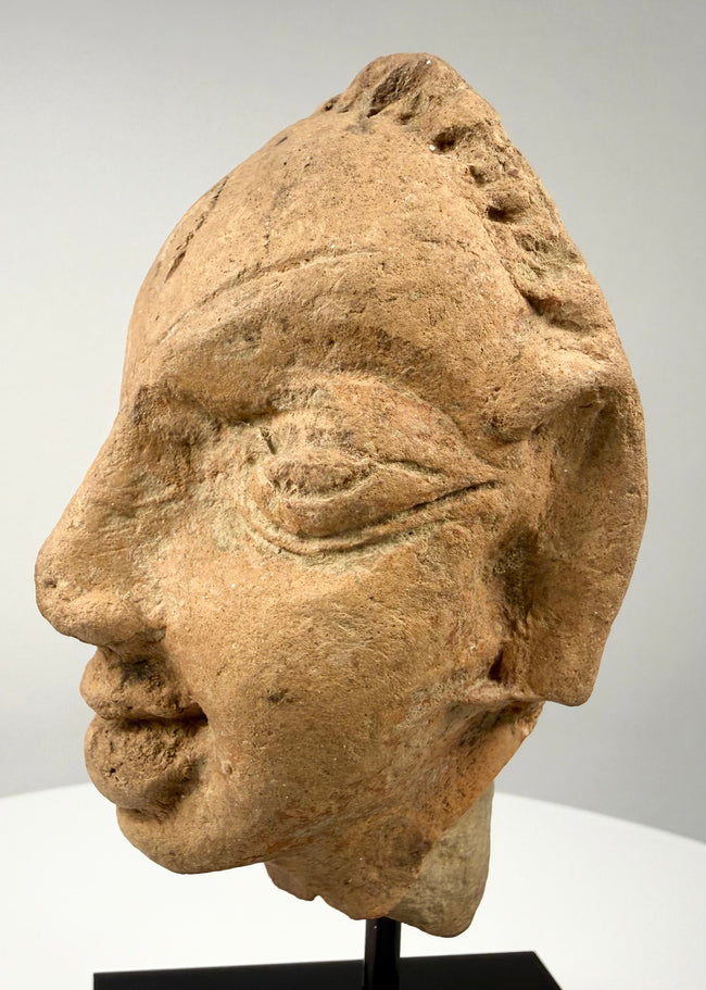 Three-quarter view of antique terracotta head displaying nose, mouth, and ear details