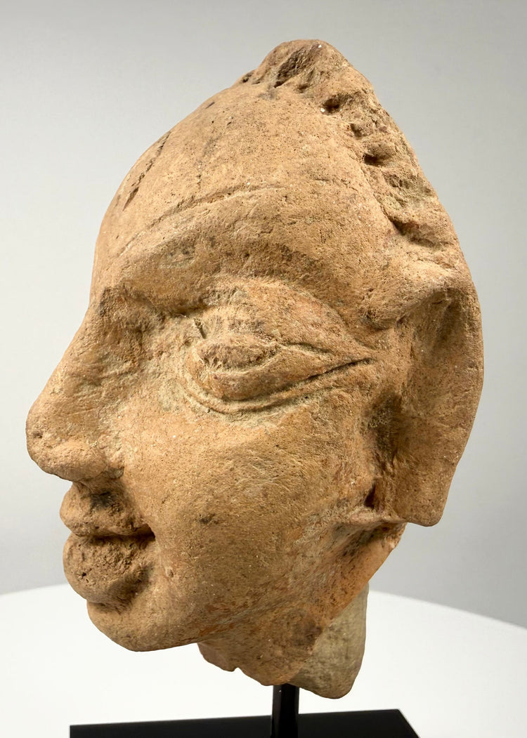Three-quarter view of antique terracotta head displaying nose, mouth, and ear details