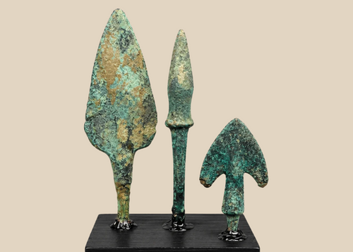 Three ancient Western Asiatic bronze projectile points mounted on a black display base