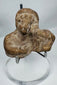 Ancient mold-made terracotta figurine fragment depicting a human bust with a headdress or hood.