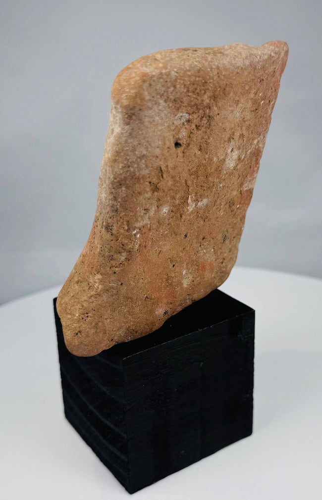 Ancient terracotta relief fragment with deeply set eyes and traces of red pigment