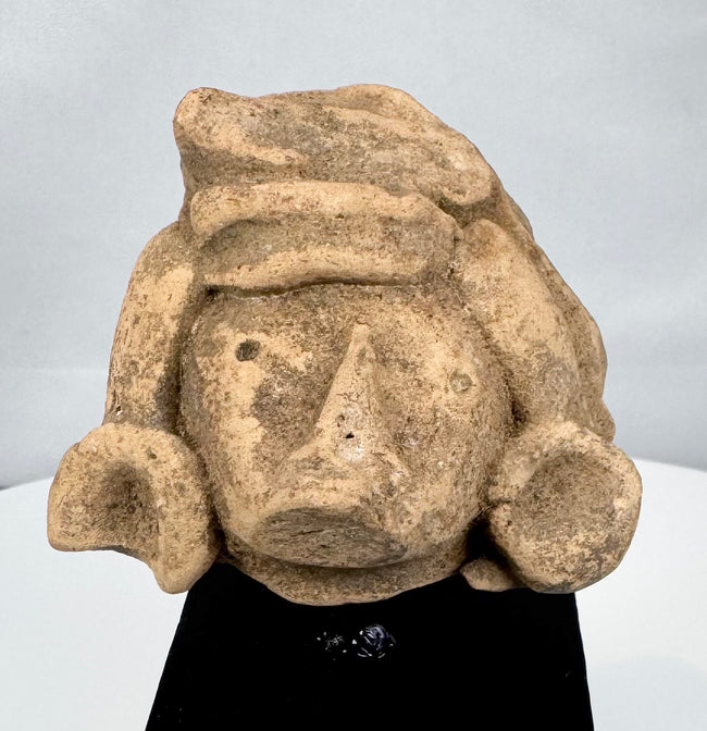Pre-Columbian stone head depicting an elite figure with earspools and ceremonial headdress