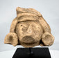 Ancient Mesoamerican stone head with elaborate headdress and weathered tan surface