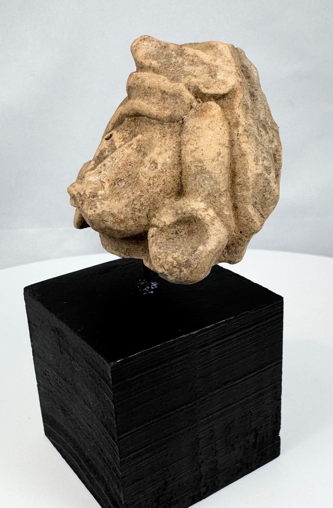 Weathered Pre-Columbian stone head with broad face and layered sculpted coiffure