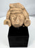 Ancient Mexican stone head with large ear ornaments and stylized facial features