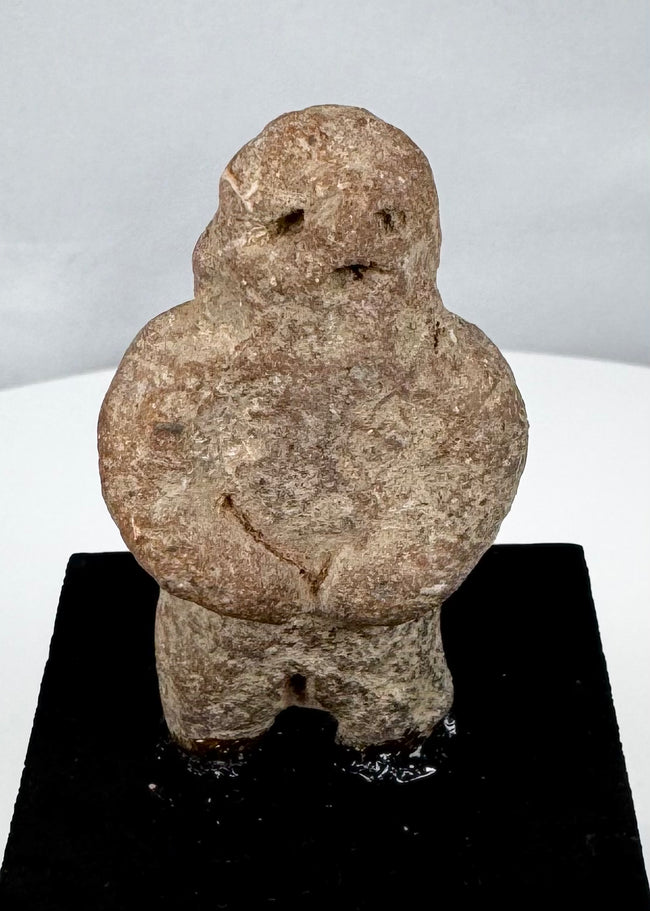 Stylized Pre-Columbian stone figure with rounded torso, short legs, and folded arms