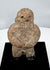 Stylized Pre-Columbian stone figure with rounded torso, short legs, and folded arms