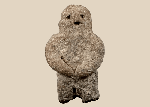Pre-Columbian carved stone standing figure with folded arms and deeply recessed eyes