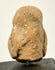 Rear view of ancient terracotta fragment with sandy texture and visible repair patch on upper back
