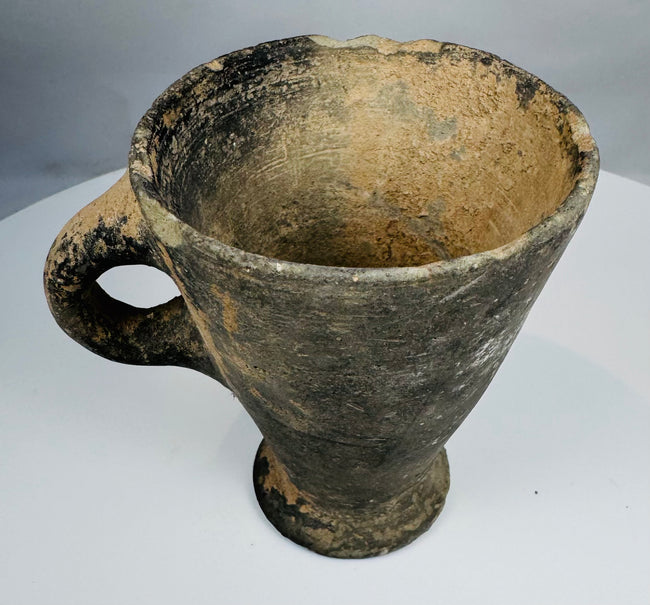 Ancient Western Asian handled ceramic cup with mineral accretions
