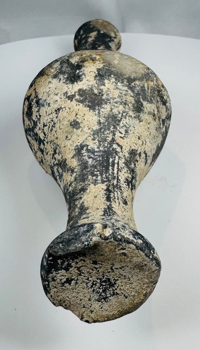 Close-up of dark burnished pottery surface with pale mineral accretions