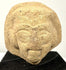 Angled view of ceramic artifact emphasizing grainy material texture and carved eyes