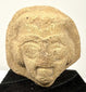 Close-up of beige clay sculpture showing prominent brow ridge and mouth details