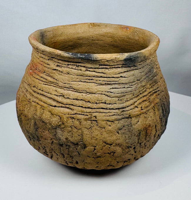 Hand-built Casas Grandes pottery jar dating to circa 1100–1450 CE, displaying traditional corrugated ceramic construction and warm buff coloration.