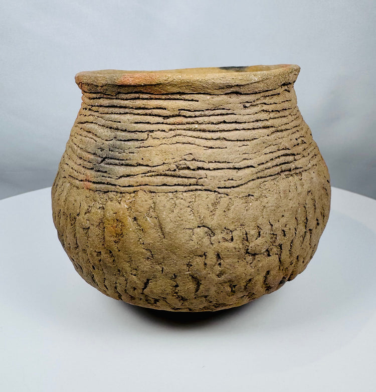 Historic Casas Grandes ceramic vessel from northern Mexico with wide mouth opening, corrugated shoulder bands, and mineral deposits.