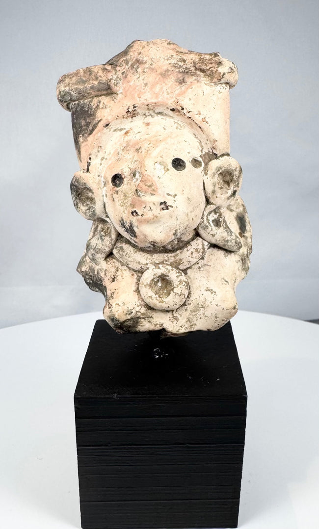 Pre-Columbian ceramic head with perforated eyes, ear ornaments, and ceremonial headdress