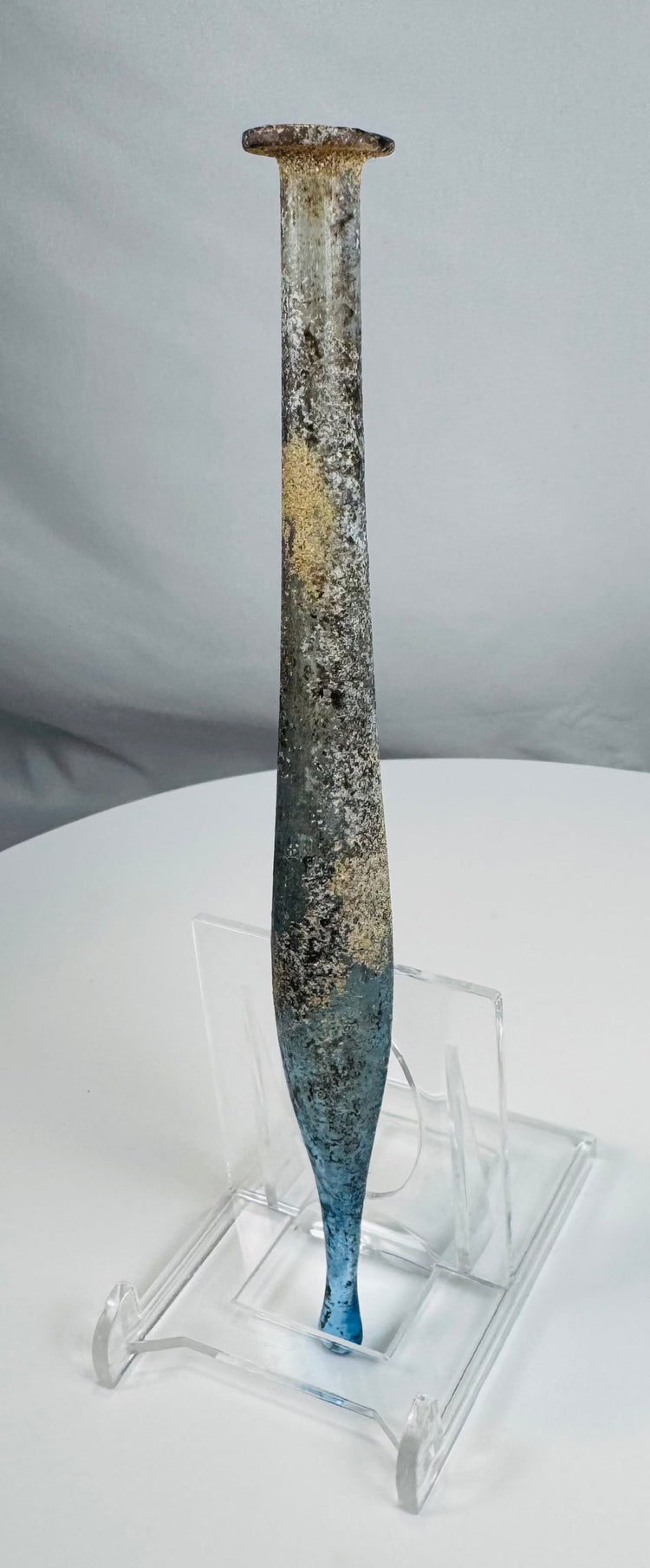 Ancient free-blown blue glass vessel from the Roman Empire with elongated spindle-shaped body