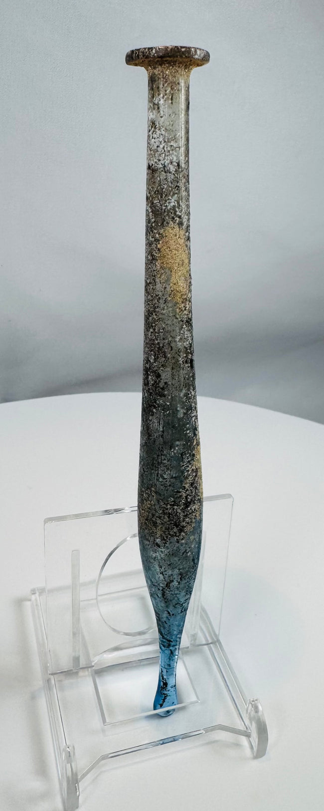 Ancient Roman pale blue glass candlestick unguentarium displaying archaeological weathering and iridescence