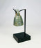 Detailed photograph of Roman bronze bell with worn surface and intact suspension loop.