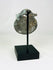 Photograph of back view of rounded Roman bronze pendant used as a protective or symbolic charm.