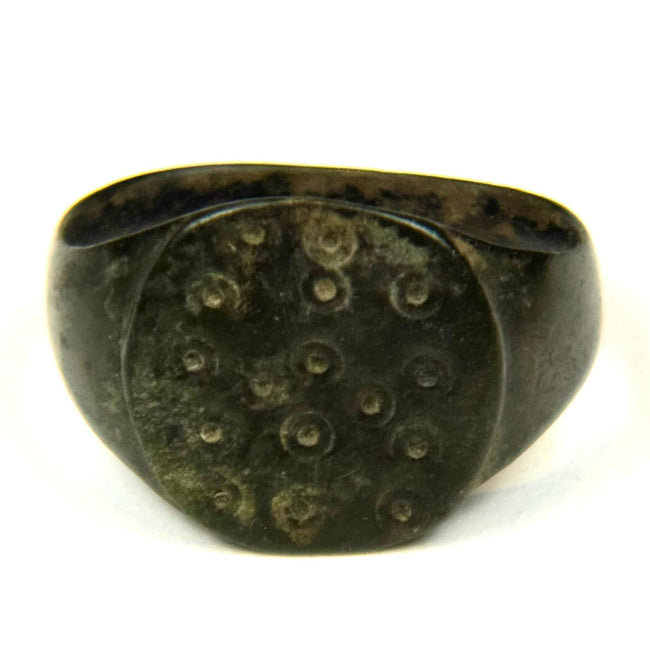 Roman bronze finger ring featuring irregular ring-and-dot decoration across the flat bezel