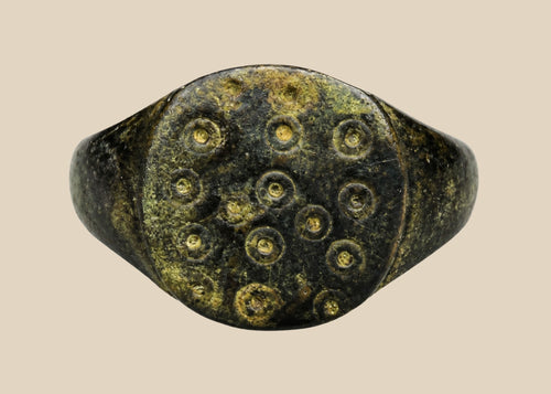 Ancient Roman bronze ring, size 7 US, featuring a flat bezel engraved with irregular “ring and dot” motifs symbolizing the sun, with authentic patina and well-preserved surface from the 1st–3rd century CE.