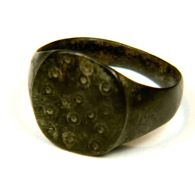 Bronze Roman ring with ring-and-dot engraving, weathered surface texture, and historic patination
