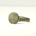 Rear view of ancient bronze ring showing intact hoop, mineral deposits, and localized reddish-brown oxidation