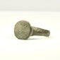 Rear view of ancient bronze ring showing intact hoop, mineral deposits, and localized reddish-brown oxidation
