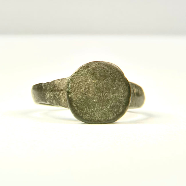 Side profile of ancient bronze finger ring with raised circular bezel and narrowing hoop, Eastern Mediterranean origin