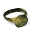 Close view of ancient bronze ring showing broad flat bezel, irregular handmade profile, and mineralized surface deposits