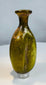 Ancient Roman glass flask displaying mineral deposits, iridescence, and olive green coloration