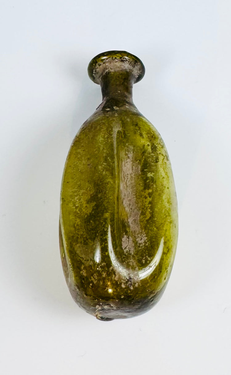 Ancient hand-blown Roman glass flask with fluted body and naturally weathered olive green surface