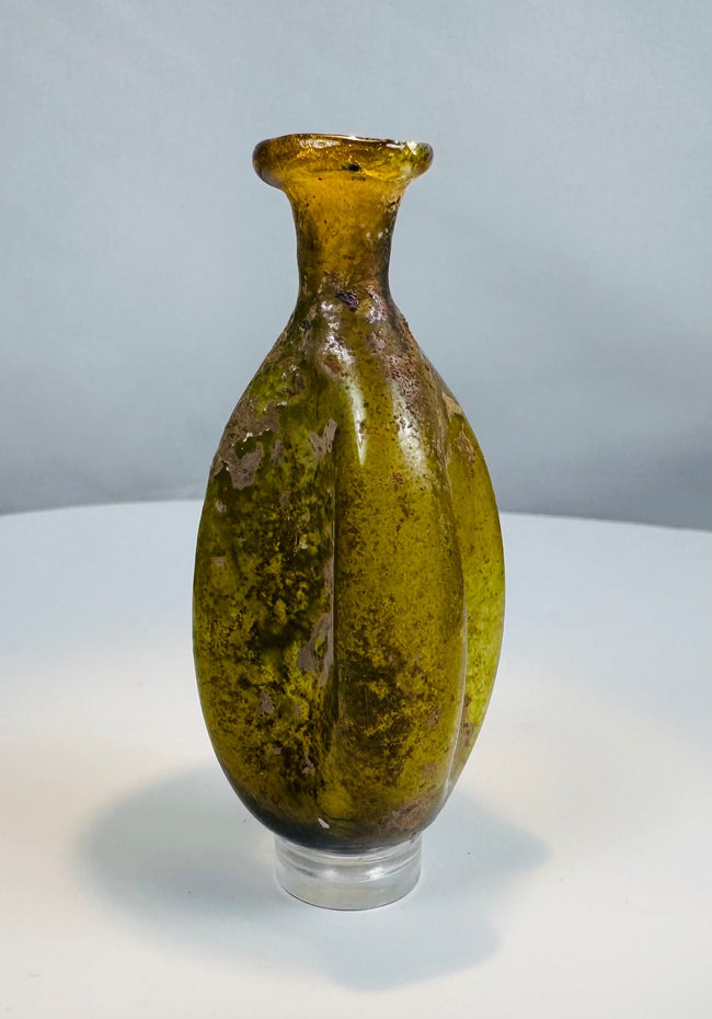 Free-blown Roman glass flask with fluted body, flared rim, and archaeological weathering