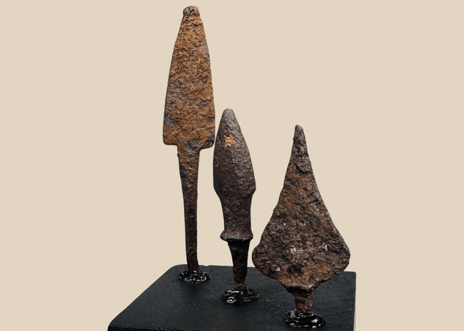 Three ancient Roman iron projectile points mounted on a black display base
